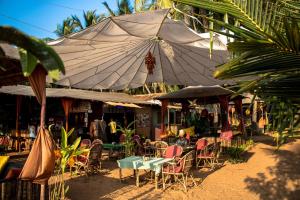 an outdoor cafe with tables and chairs and an umbrella at Sonho do Mar in Agonda +31 photos