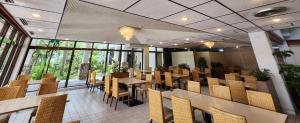a dining room with tables and chairs and windows at Resort Hotel Kume Island in Kumejima