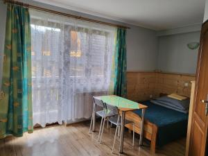 Habitación con cama, mesa y ventana en Willa Anda, en Zakopane