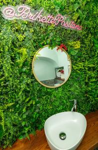 a mirror on a green wall above a sink at Hostel Brikette in Positano