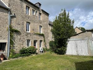 an old stone building with a gate and a tree at Appartement RDC Dinan in Dinan