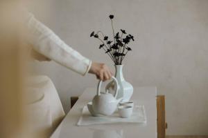 eine Person, die Tee in eine Vase auf einen Tisch gießt in der Unterkunft Onyouji Stay in Busan
