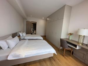 two beds in a room with a desk and a bed at May Seven Hotel and Suites in Ulaanbaatar