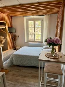 une chambre avec un lit et un vase de fleurs sur une table dans l'établissement Les Glycines, charmant studio au calme dans bâtisse de Maître proche du centre ville parking gratuit, à Digne-Les-Bains 26 autres photos