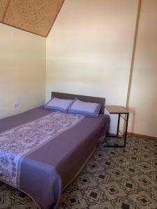 Un dormitorio con una cama con almohadas azules y una mesa. en Котедж біля моря, en Odessa