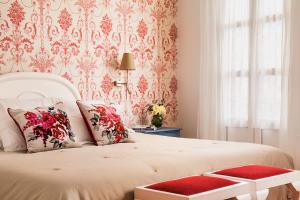 a bedroom with a white bed with a red and white wallpaper at Hotel Infanta Isabel by Recordis Hotels in Segovia