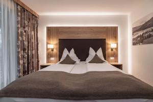 a bedroom with a large bed with pillows at Alpen Adria Hotel & Spa in Presseggersee