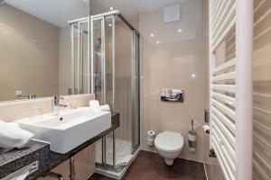 a bathroom with a sink and a toilet at Alpen Adria Hotel & Spa in Presseggersee