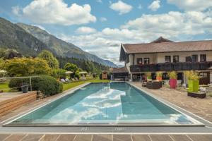 a large swimming pool in front of a house at Alpen Adria Hotel & Spa in Presseggersee