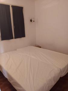 ein weißes Bett in einem Zimmer mit Fenster in der Unterkunft Appartement cosy à Grosseto-Prugna - Vue sur la mer, 42 m² in Grosseto-Prugna
