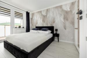 um quarto com uma cama grande e lençóis brancos em Jantar Apartamenty - Miodowy Dom City Center em Kolobrzeg