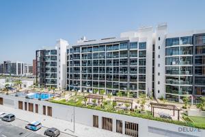 an apartment building with a pool and a parking lot at Charming Studio at Azizi Riviera 32, Al Merkadh by Deluxe Holiday Homes in Dubai