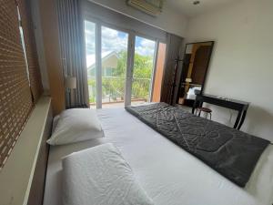 a bedroom with two beds and a large window at บ้านบางเตยริมน้ำพูลวิลล่า in Ban Bang Rathuk