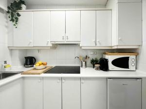 eine weiße Küche mit weißen Schränken und einer Mikrowelle in der Unterkunft BALCÓN AL MEDITERRÁNEO Y SKYLINE DE BENIDORM in Benidorm