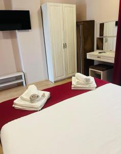 - une chambre avec un lit blanc et des serviettes dans l'établissement Friday Hotel, à Mamaia Nord – Năvodari