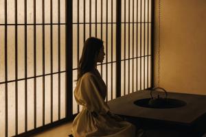 釜山的住宿－Onyouji Stay，坐在窗前的女人的雕像