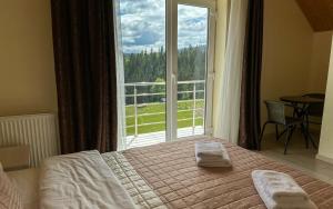 um quarto com uma cama e uma grande janela em Шепіт Лісу em Bukovel