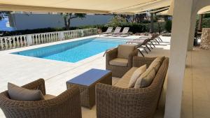 a swimming pool with wicker chairs and a table at Villa HERMITAGE in Binissafuller