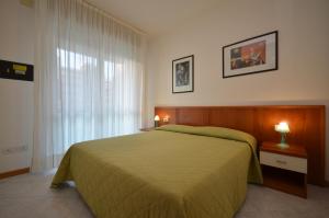 ein Schlafzimmer mit einem grünen Bett und einem Fenster in der Unterkunft Appartamenti Torre Del Sole in Bibione