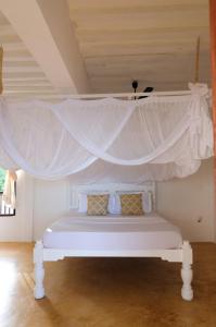 1 dormitorio con 1 cama blanca con dosel en Shela Bahari, en Shela