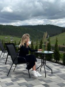 a woman sitting at a table talking on a cell phone at Шепіт Лісу in Bukovel