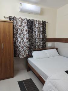 niewielka sypialnia z łóżkiem i zasłoną w obiekcie Janardhana Residency w mieście Dharmastala
