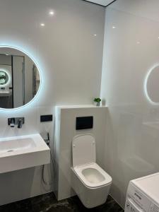 uma casa de banho com um WC, um lavatório e um espelho. em Люкс апартаменти в ЖКАрена em Rivne