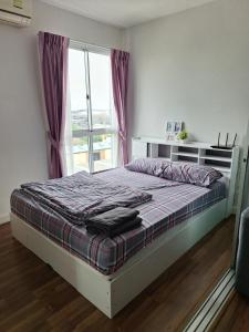 a bedroom with a bed and a window with purple curtains at Mari Space in Nonthaburi