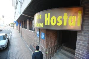 mężczyzna przechodzący obok szpitalnego znaku na budynku w obiekcie Hostal Santa Barbara w mieście Soria