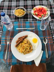 a plate of food with sausage and rice on a table at Lucky's Homestay in Maho
