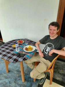 un hombre sentado en una mesa con un plato de comida en Lucky's Homestay en Maho