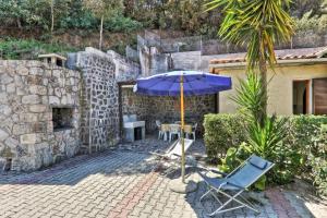 a patio with a blue umbrella and a table and chairs at Casa Helba - Colle Paradiso Experience in Capoliveri +3 photos