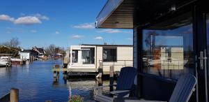 a house sitting on a dock on a body of water at Poellodge, Luxe houseboot met zonnig terras in Aalsmeer