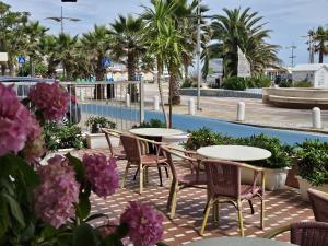 a patio with tables and chairs and purple flowers at Hotel Villa Rosa in Misano Adriatico