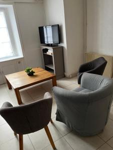 a living room with chairs and a table and a tv at Gîte Les Hortensias in Morlaix