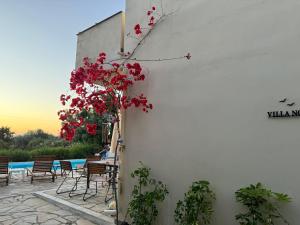 a white building with red flowers on the side of it at Villa Nova s.r Sea View in Porto Heli