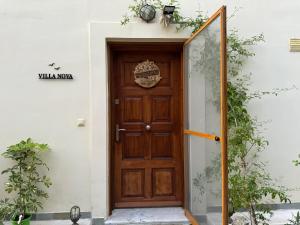 a wooden door on a white building with plants at Villa Nova s.r Sea View in Porto Heli