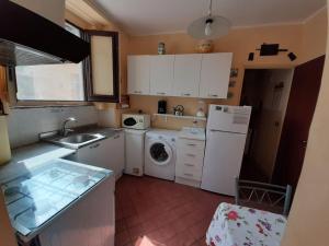 a kitchen with a white refrigerator and a washing machine at Lemon's House by the sea in Pozzillo +15 photos