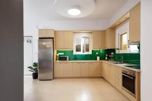 cocina con paredes verdes y nevera de acero inoxidable en Villa Emily Rethymno, en Adelianos Kampos