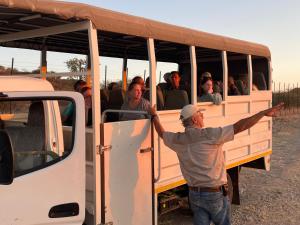 un hombre de pie junto a un autobús lleno de gente en Aloegrove Safari Lodge, en Otjiwarongo