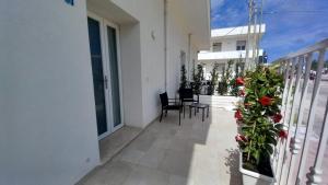 a balcony of a white building with chairs and flowers at B&B Bonomi in Torre Lapillo