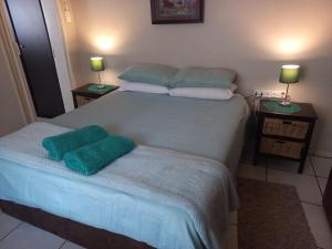 a bedroom with a bed with two green pillows on it at Wildepeer in Nelspruit