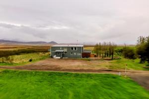 ein grünes Haus mitten auf einem Feld in der Unterkunft The Hvítá Inn in Bær