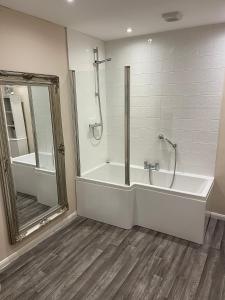 een badkamer met een bad, een douche en een spiegel bij Market Hill Apartments in Royston