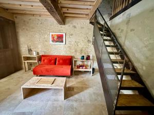 sala de estar con sofá rojo y escalera en Borderie de Vérone, en Espiens