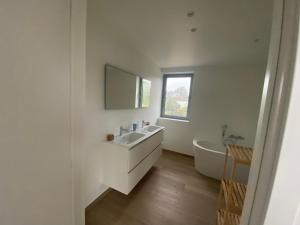 a bathroom with a sink and a tub and a mirror at Den Eenink in Zedelgem +21 photos