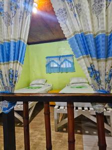 two beds in a room with blue and white curtains at Bohol Sea Breeze Cottages and Resort in Panglao
