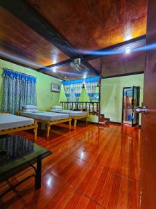 a room with two beds and a wooden floor at Bohol Sea Breeze Cottages and Resort in Panglao Island