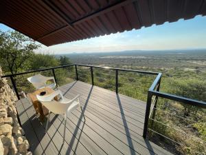 balcón con 2 sillas, mesa y vistas en Aloegrove Safari Lodge, en Otjiwarongo