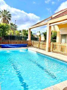 a swimming pool with blue water in front of a house at APARTBEACH EL PINAR CON PISCINA y BARBACOA in Reus